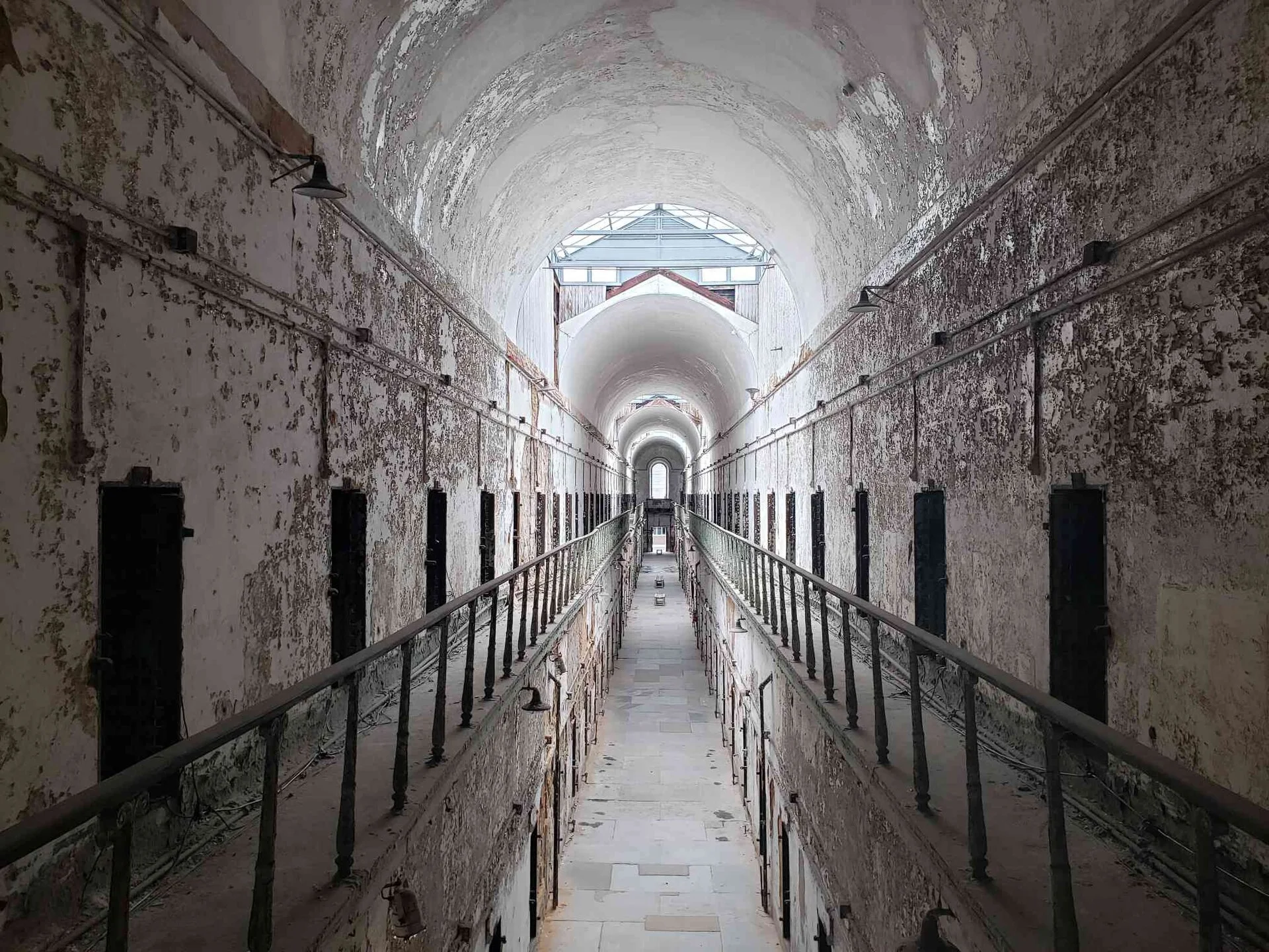 The vaulted cellblock gallery of Eastern State Penitentiary, with empty corridors receding into the distance.