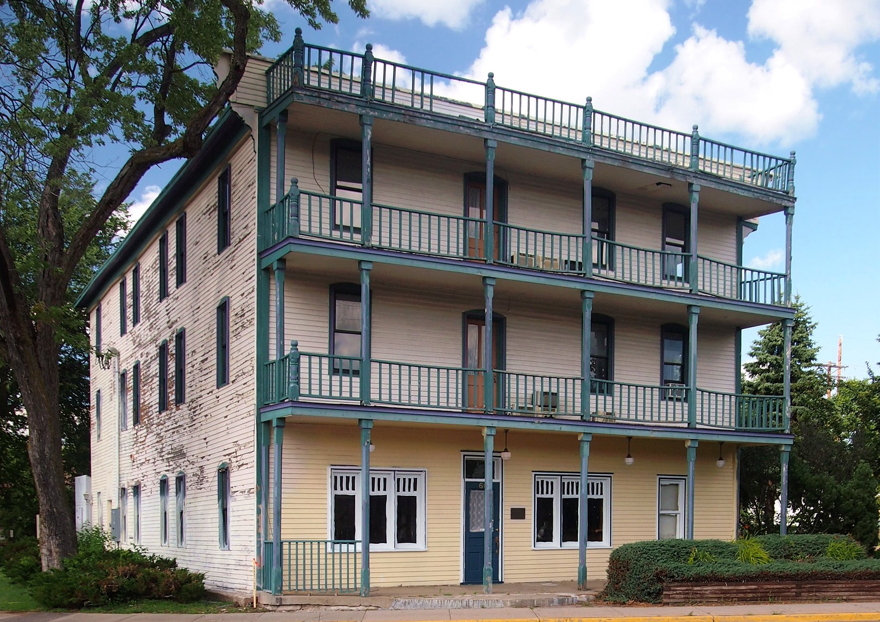 Historic Thayer Hotel exterior with three levels of green balconies in Annandale, Minnesota, in an archival 2015 view.