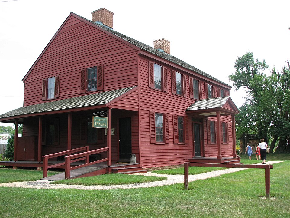 Red wooden exterior and covered porch of Surratt House Museum, Maryland.